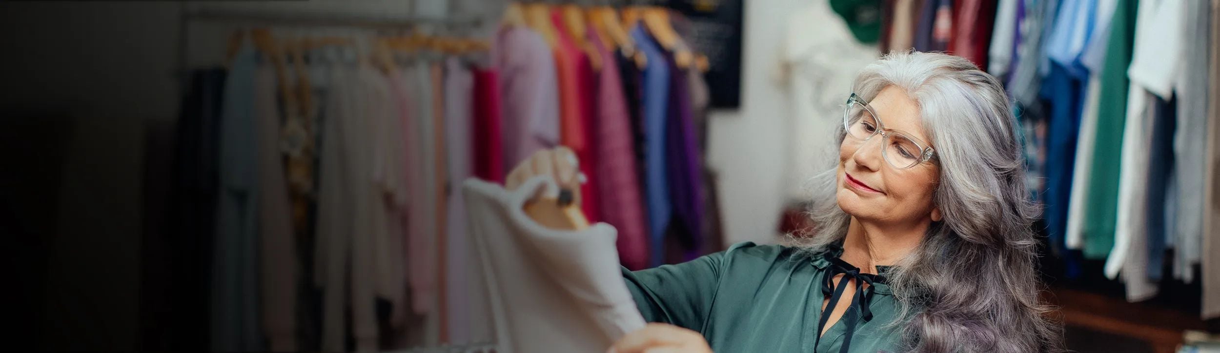 Vrouw met een bril kijkt naar kleding in een winkel